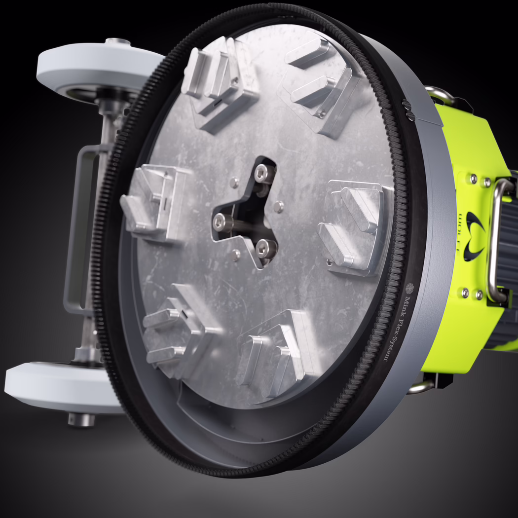 WOLFF_Application Image_NEO330_183050_2026-03 Een gedetailleerde close-up van een cirkelvormige industriële gereedschapkop met een grote ronde metalen voorplaat met zes schuine aluminium klemmen of houders, symmetrisch gerangschikt rond een centrale drie-lobbige naaf met zichtbare bevestigingen. Een zwarte, getande rubberen tandriem omsluit de buitenrand; de binnenoppervlakken tonen bewerkte en licht geschuurde metaaltexturen met zichtbare schroeven en montagepunten. Rechts zit een fel limoen groen metalen behuizing met draaghandgreep en koelribben bevestigd aan de voorplaat, wat wijst op een motorisch aangedreven roterende schuur- of polijstkop. Studiobelichting zorgt voor zachte highlights en scherpe reflecties op het metaal tegen een donkere verloopachtergrond.